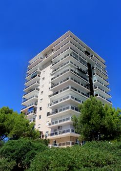 Exterior of a tall modern apartment building with blue sky background.
