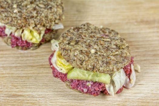 Raw burgers with beetroot and salad on a wooden background