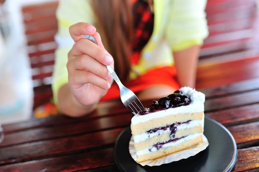 An Womenl eating fancy cake in soft light .