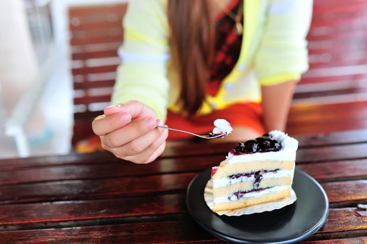 An Womenl eating fancy cake in soft light .