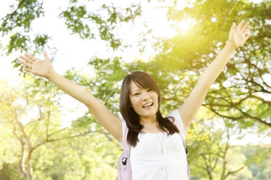 Young Asian college girl student standing on campus lawn, open arms and smiling.