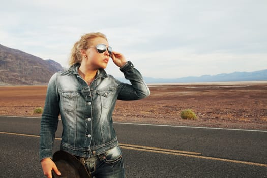 portrait of young beautiful girl is waiting for the car  in desert environment