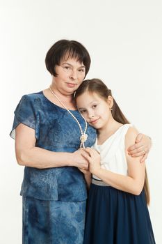 the grandmother and the granddaughter stand in dresses having embraced