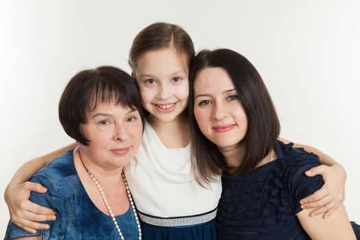 The granddaughter embraces the grandmother and mother on a white background