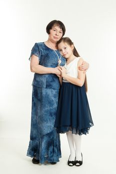 the grandmother and the granddaughter stand in dresses having embraced