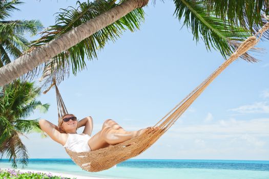 view of nice young lady swinging  in hummock on tropical beach