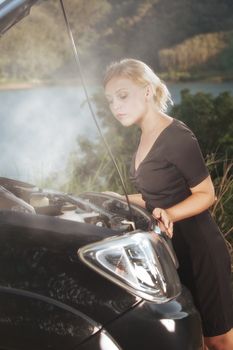 portrait of young beautiful woman with broken car aside