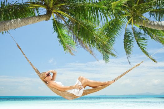 view of nice young lady swinging  in hummock on tropical beach