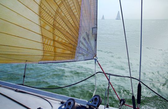 Sail against blue sky, sea and yachts