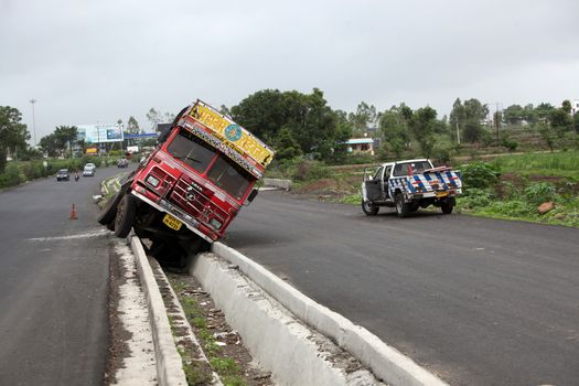 Pune, India - June 27, 2015: An truck that went out of control on an Indian highway and fell in storm drainage canal.