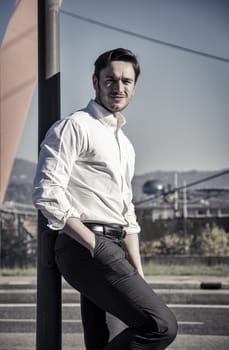 Handsome young man outside wearing white shirt, looking to a side. Profile view, day shot.