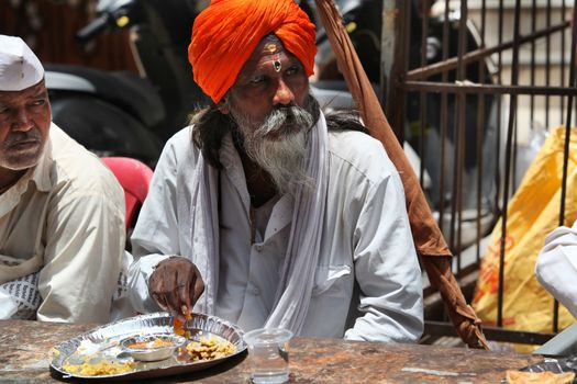 Pune, India  - ‎July 11, ‎2015: A hindu pilgrim having a meal served to him by a charitable organization, during the Wari festival in India.