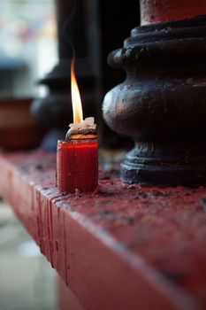 close up view of red candle burning out in shrine environment