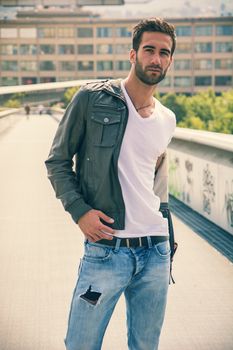 Handsome bearded young man outdoors in urban environment looking at camera