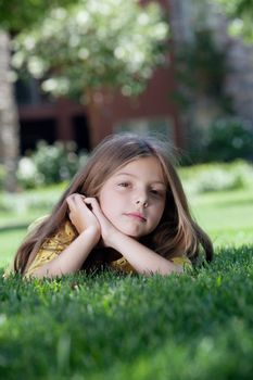 portrait of little girl laying on the grass in summer environment