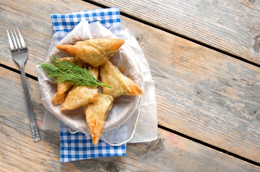 Greek cheese stuffed filo pastry with herbs in a dish on a wooden background with space