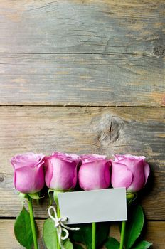Pink flowers on a wooden backdrop with a blank gift tag  and copyspace 