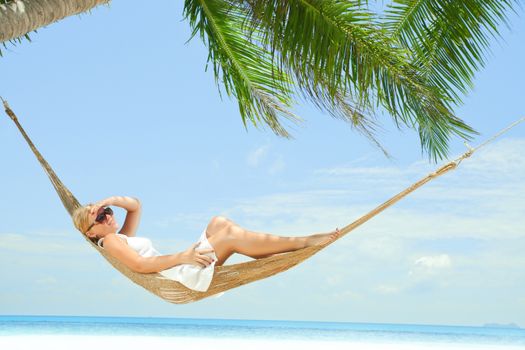 view of nice young lady swinging  in hummock on tropical beach