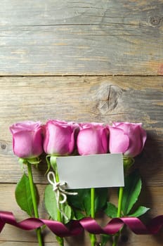 Pink  flowers on a wooden background wtih gift tag and space for text