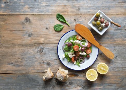 Greek salad with kalamata olives and feta cheese on top of a wooden table with space