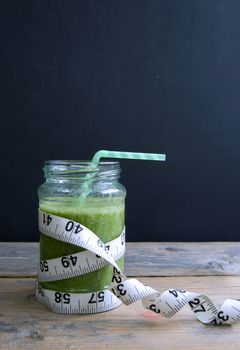 Healthy green smoothie with measuring tape 