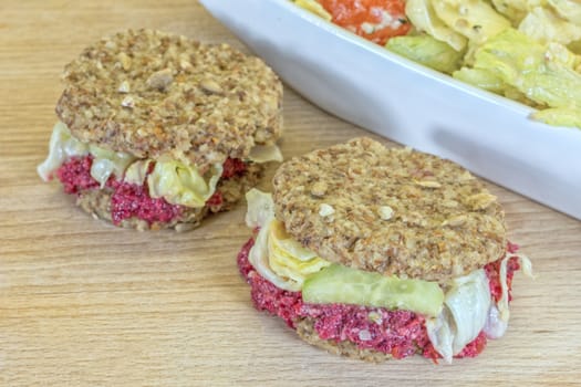 Raw burgers with beetroot and salad on a wooden background