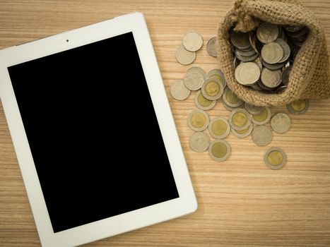 tablet computer and coins bag.  Financial Planning concept.