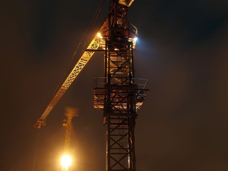 construction site with cranes and illumination at night, long exposure
