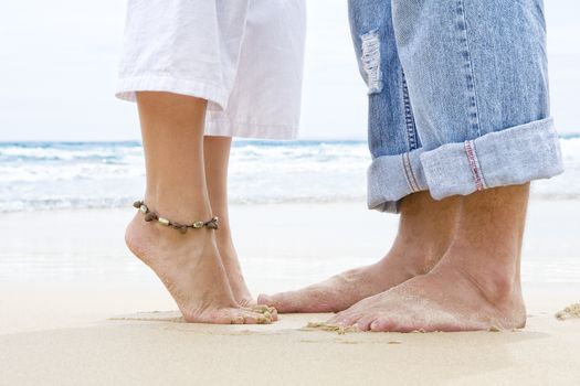 Close up view of  pair of human’s feet on sandy beach back