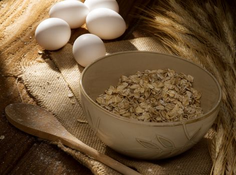 close up view of oat flakes with eggs and  wheat on color back