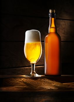 close up view of  glass full of beer and bottle on color background