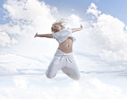 Portrait of young jumping woman on blue sky background