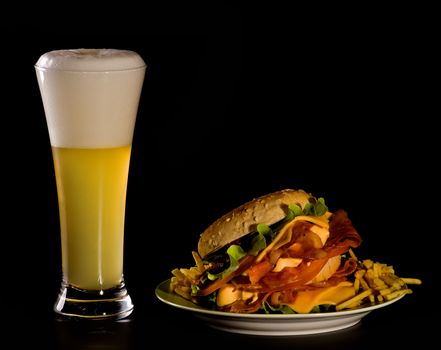 Delicious Big Burger with Grilled Bacon, Cheese, Lettuce and French Fries  and Glass of White Beer Glass isolated on Black background