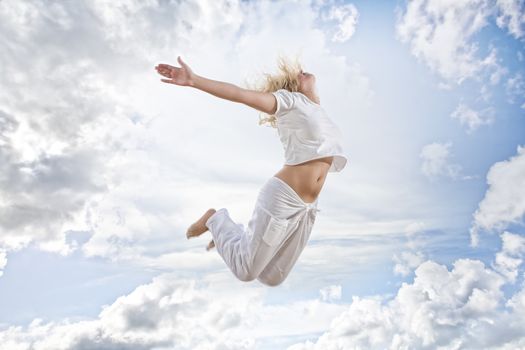 Portrait of young jumping woman on blue sky background