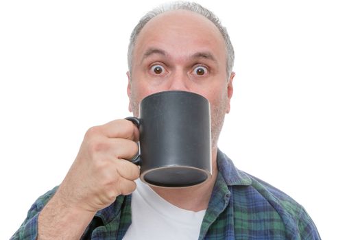 Single balding and bearded shocked man holding dark coffee mug in front of face with wide open eyes over white background