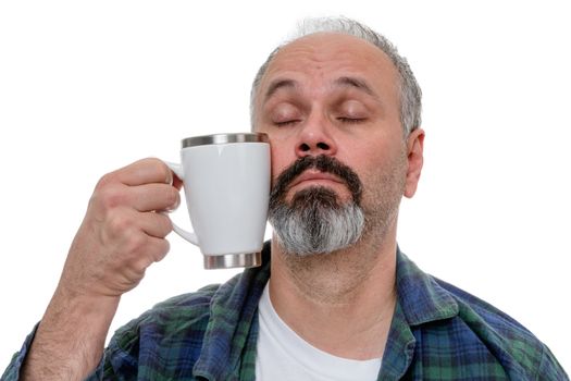 Sleepy middle aged man with receding hairline and beard struggling to bring a coffee mug to his mouth after awakening