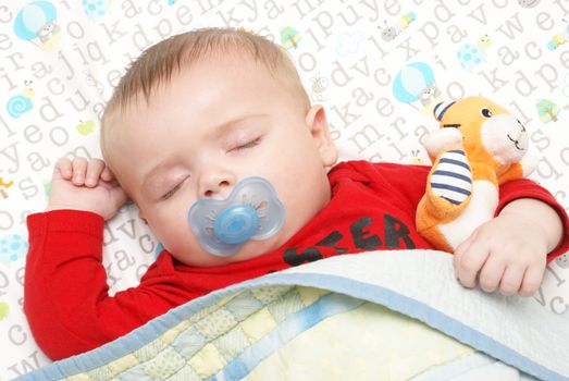 An adorable baby boy of five months is dreaming away during his peaceful sleep in his crib.