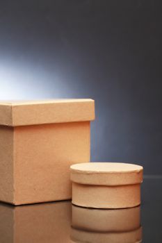 Two closed cardboard boxes with reflection on dark background