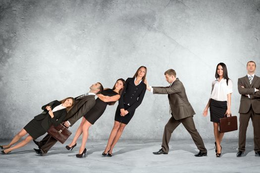 Businessman holding falling business people on grey wall background, co-working concept