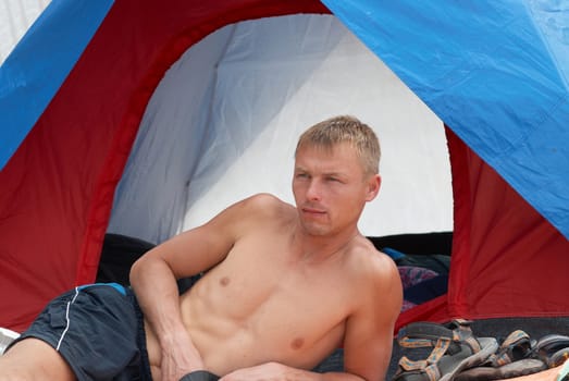 Man in the shorts lying near tent