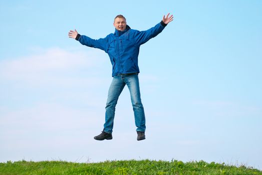 Jumping man on the hill with green grass