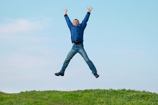 Jumping man on the hill with green grass