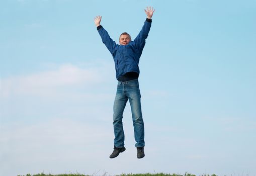 Jumping man on the hill with green grass