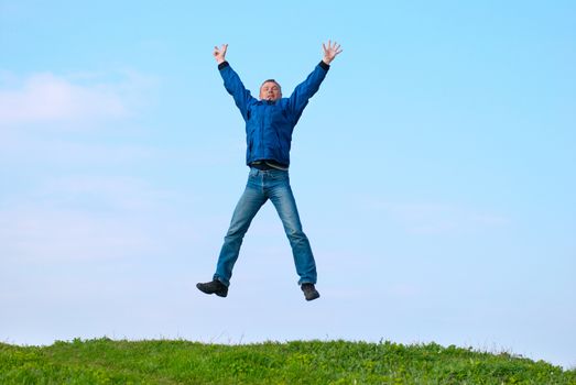 Jumping man on the hill with green grass