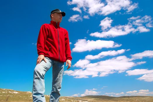 Hiker on the field against sun and cloudscape