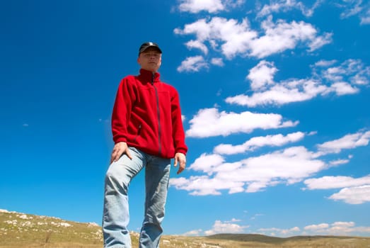 Hiker on the field against sun and cloudscape