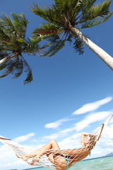 Beautiful woman resting in hammock on tropical beach of Thailand