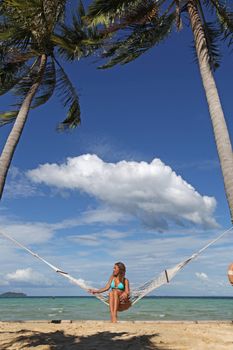 Beautiful woman resting in hammock on tropical beach of Thailand