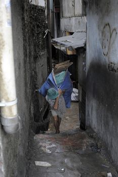 INDONESIA, Jakarta: A woman carries a bag full of planks  in the Kalijodo red-light district, in the Penjaringan subdistrict on the border of North and West Jakarta, on February 26, 2016.

Part of its inhabitants have started to leave the neighborhod as Indonesian authorities are about to demolish it. Bulldozers should start their work on Monday February 29. The neighborhood is home to about 3,000 people, including legal businesses and families. Hundreds face eviction for living among illegal brothels.