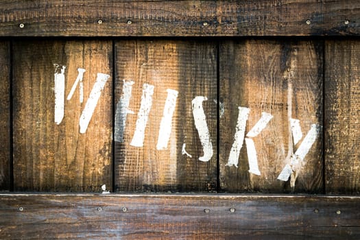 Detail of an old wooden box containing bottles of whiskey.